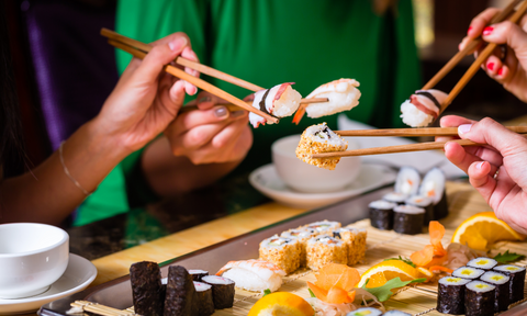 Sushi in Stäbchen werden in Gesellschaft verspeißt